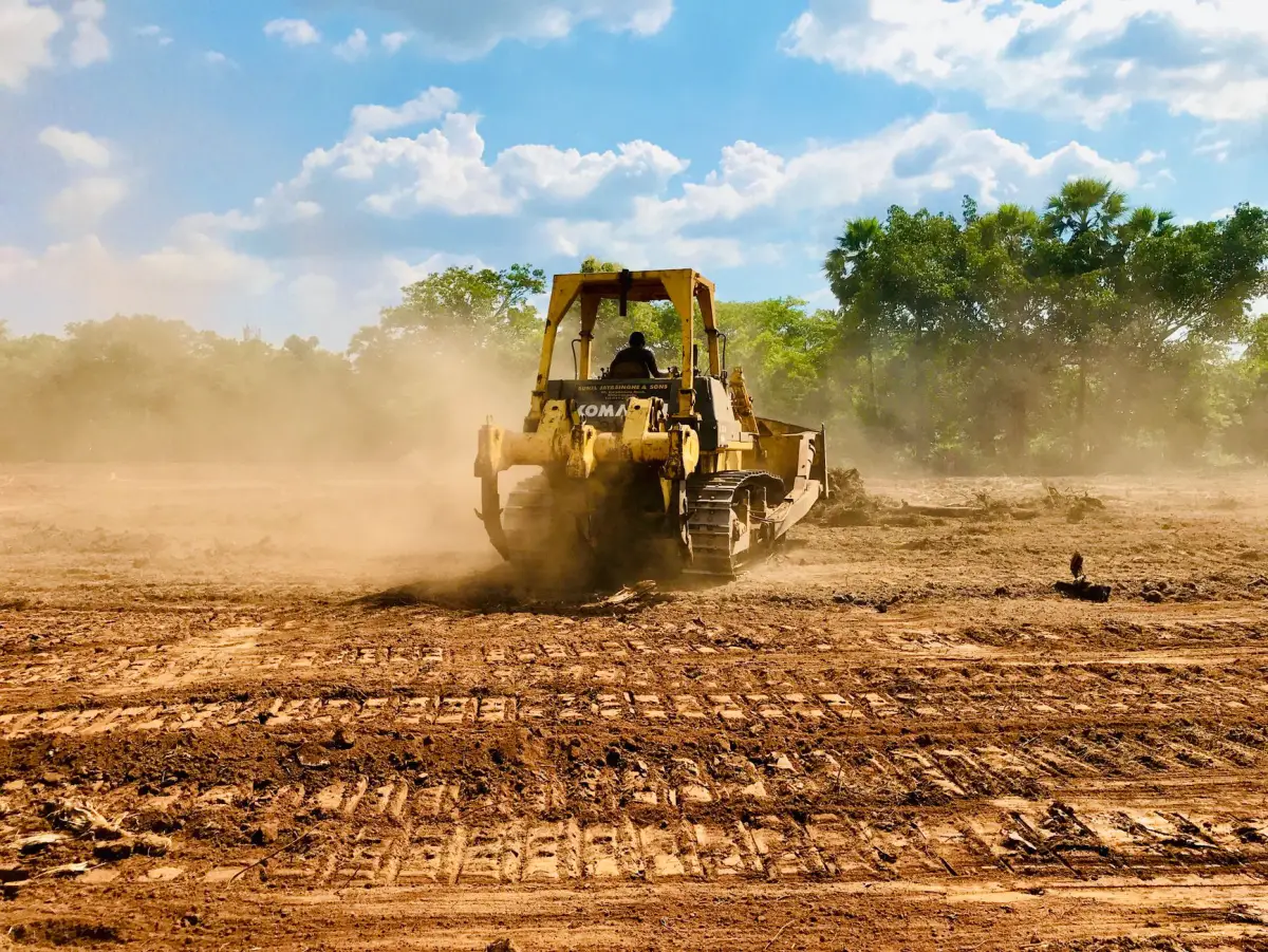 A bulldozer moving earth on a dusty commercial construction site