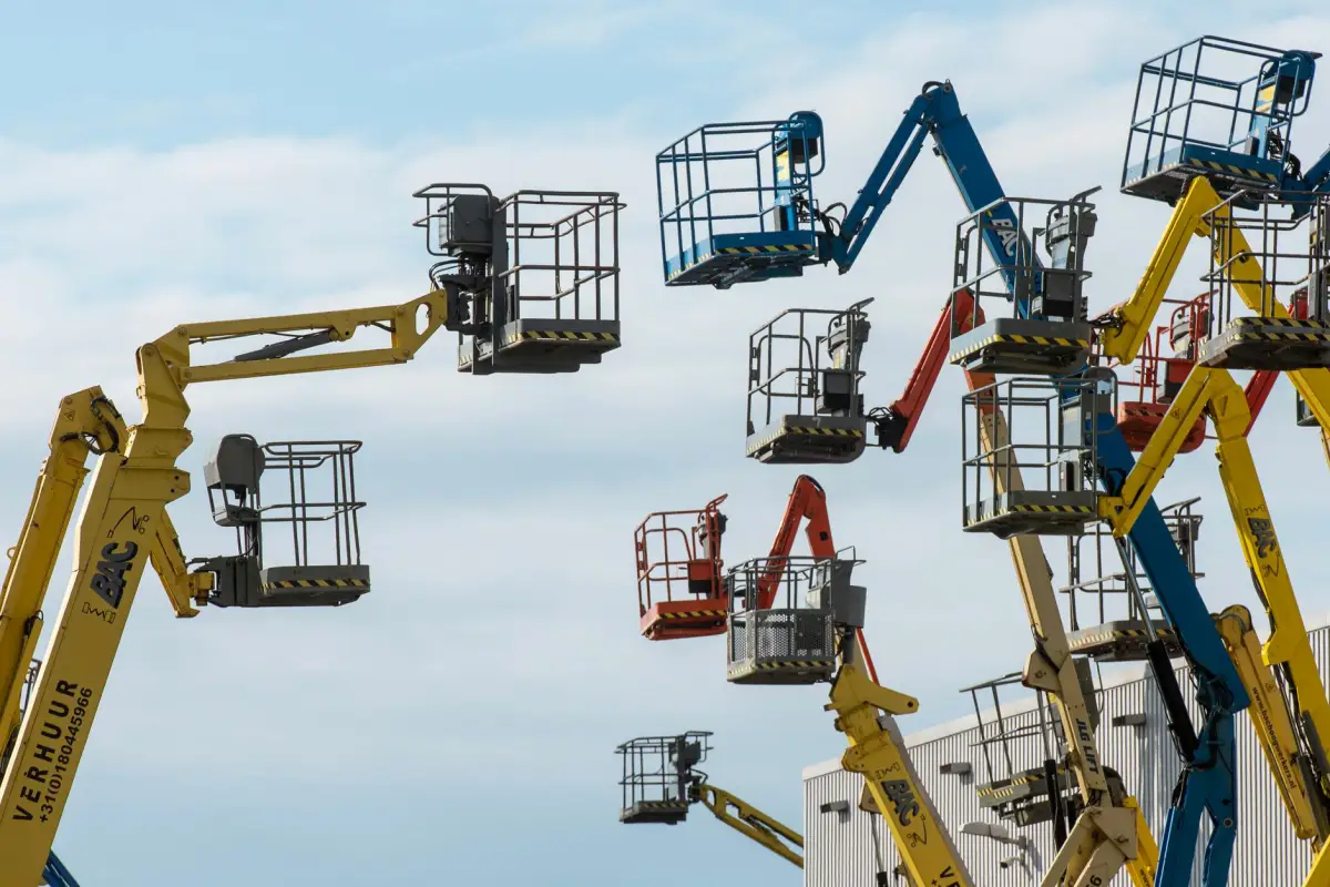 Boom lifts raised against a clear sky, the equipment used for commercial crown work